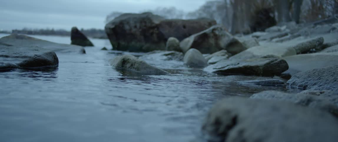 Water ripples and splashes around rocks near shore
