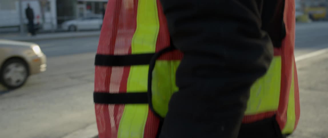 A traffic guard holds a stop sign on a street corner