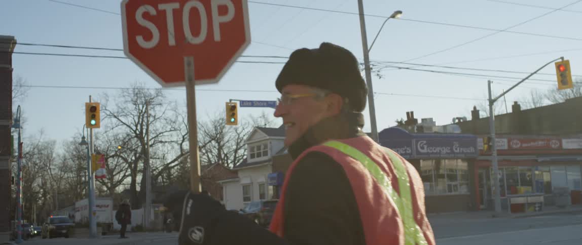 Crossing guard holds a stop sign under a blue sky