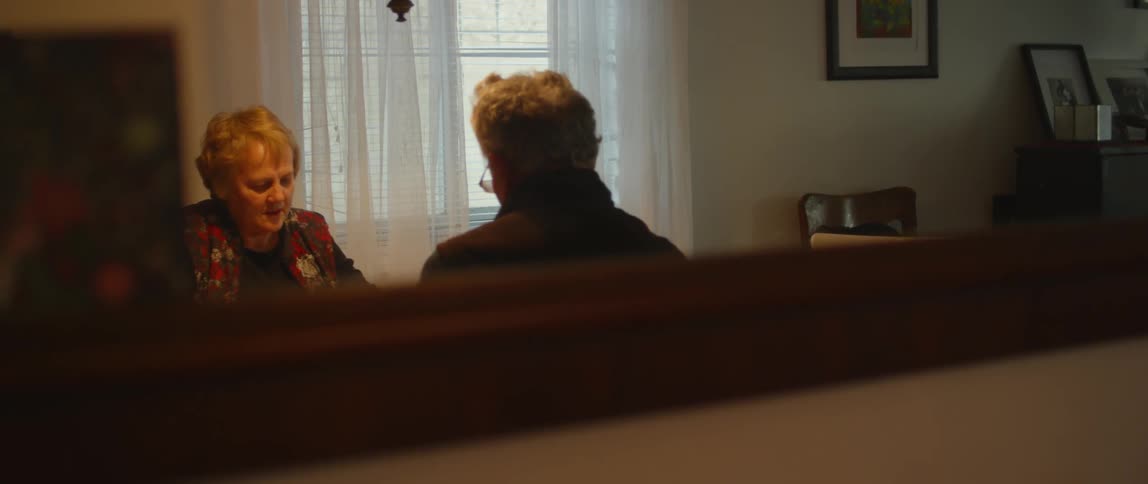 An elderly man and woman sit at home