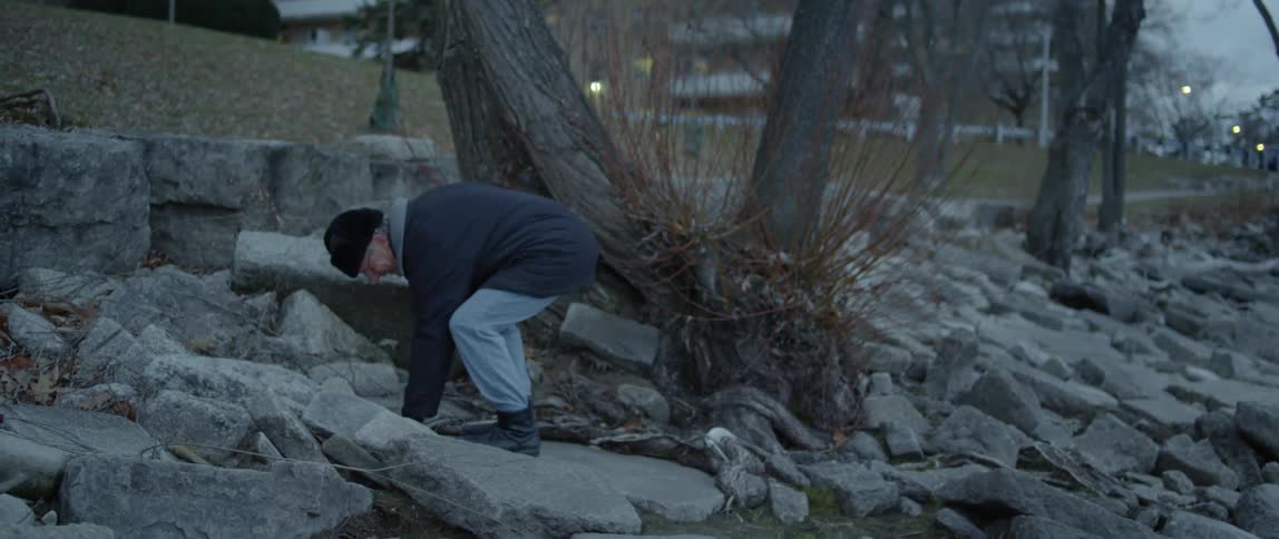 A man walks on the rocks by the water