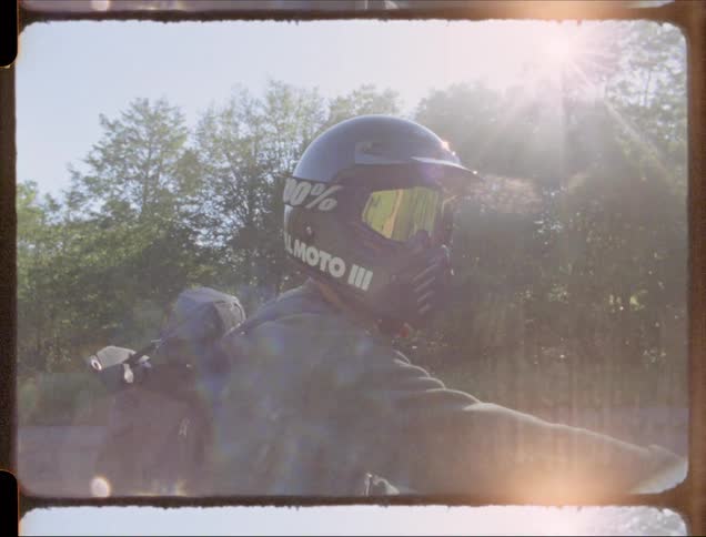 A motorcyclist rides on a rural road on a sunny day