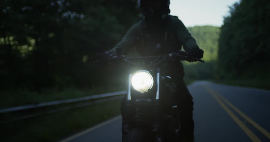 Person riding motorcycle on highway surrounded by trees