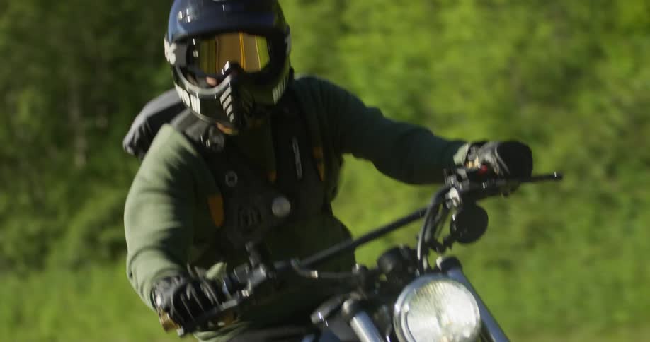 A man rides a motorcycle on a woodsy road