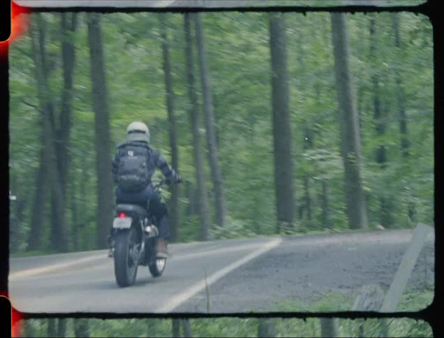 A man rides a motorcycle on a forest road