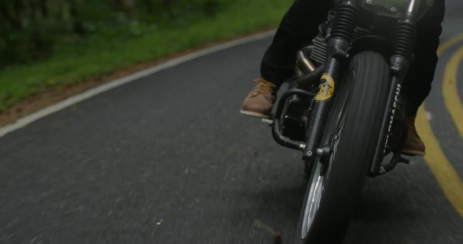 A man rides a motorcycle on a woodsy road
