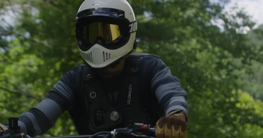 A man wearing a helmet rides a motorcycle on a sunny day
