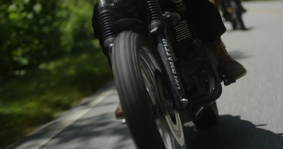 A motorcycle travels on a rural road on a sunny day