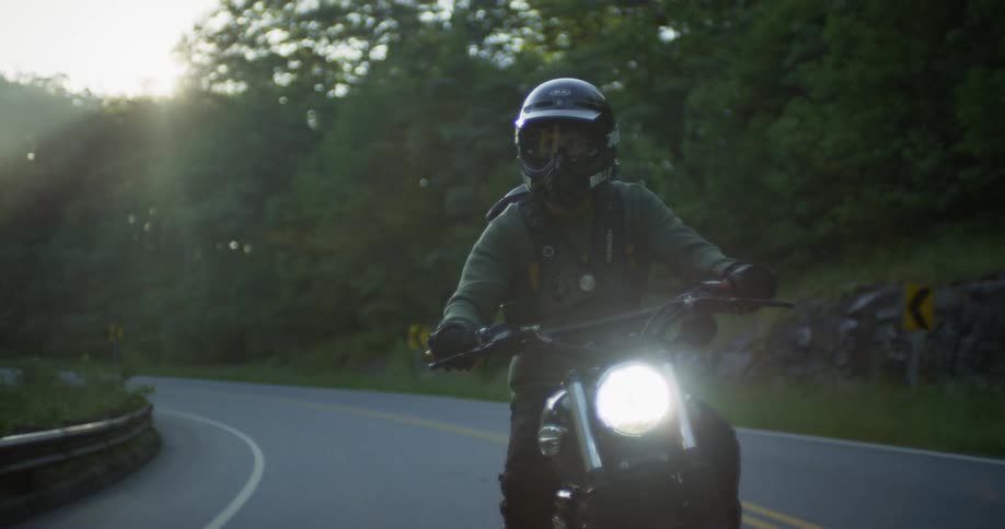 A motorcyclist rides on a rural road on a sunny day