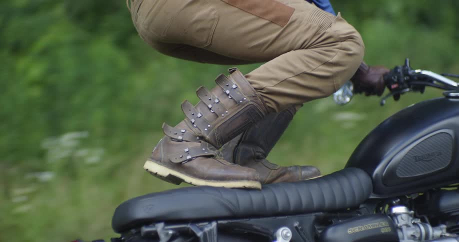 A man stands on the seat of the motorcycle