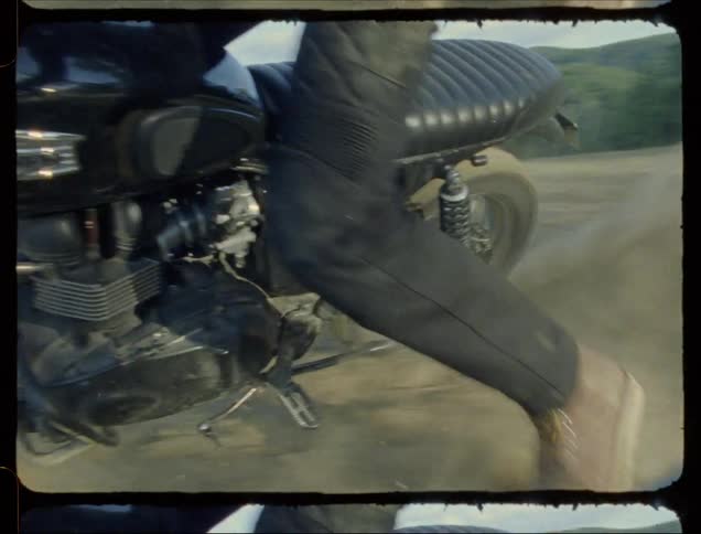 A motorcyclist kicks up dust while spinning in dirt