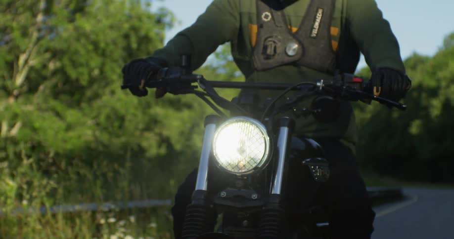 A man rides a motorcycle with its head lamp on