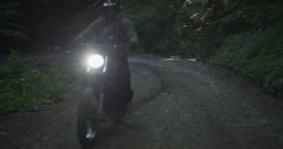 A man rides a motorcycle on a forest path