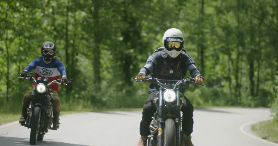 Two people are riding motorcycles on sunny highway