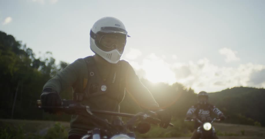 Man wears a white helmet as he sits on a motorcycle