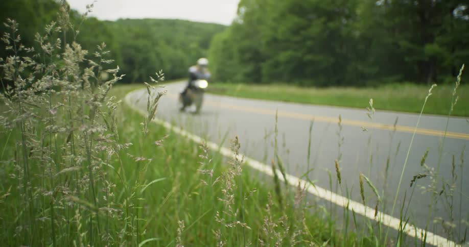 Two motorcyclists speed by on the rural road