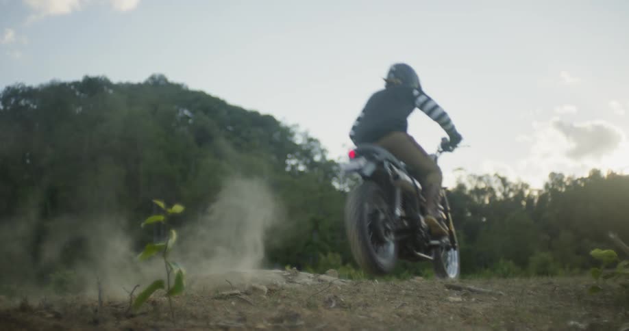 Man jumps motorcycle over dirt bump