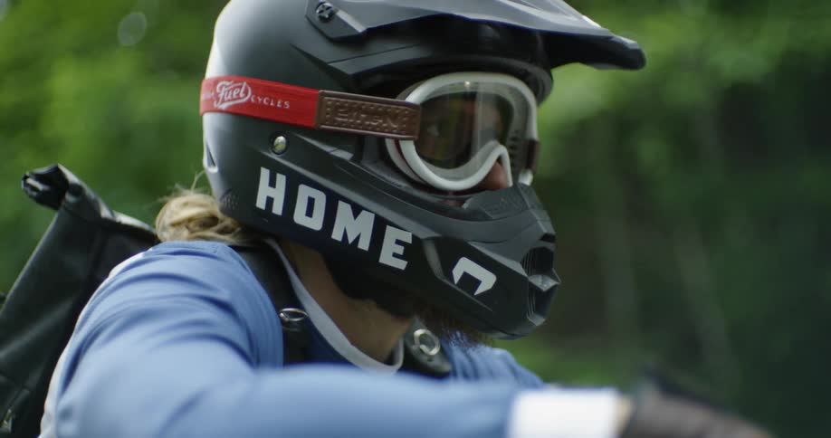 Man wearing helmet and goggles is sitting on motorcycle