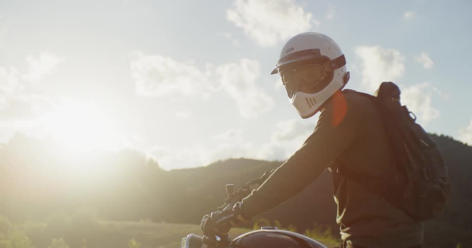 A man sitting on a motorcycle looks around on a sunny day