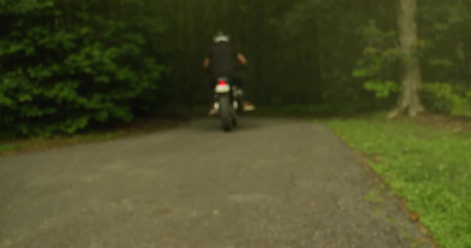 A motorcyclist rides through a forest