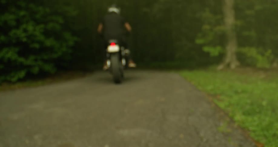The inside of an exhaust pipe and a motorcycle taking off on a dirt road