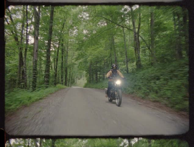A man rides a motorcycle on a forest path