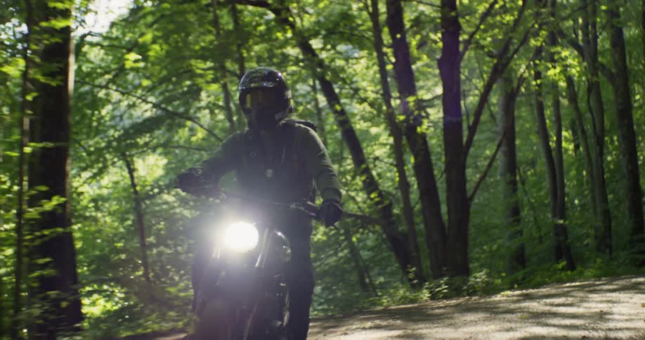 Man is riding motorcycle on dirt forest road