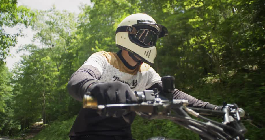 A man rides a motorcycle on a woodsy road