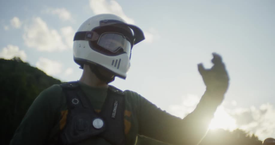A motorcyclist wears a helmet outside at sunset