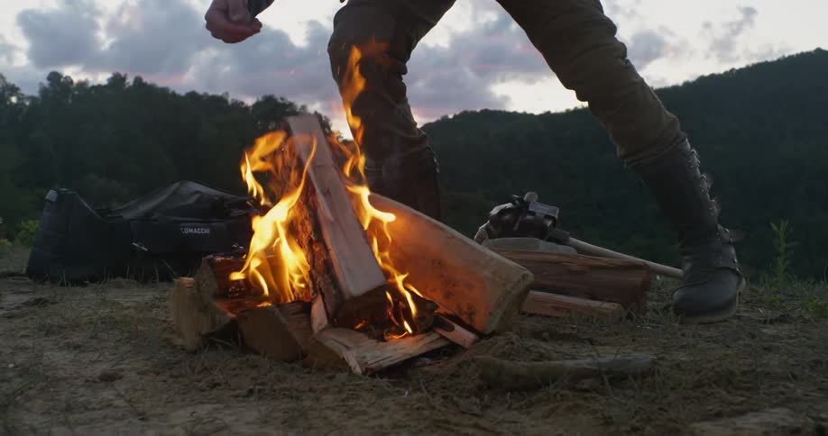 A man adds wood to a campfire