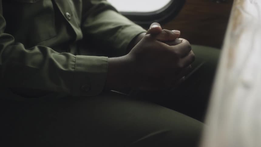 An airman sitting on a trolley clasps his hands together