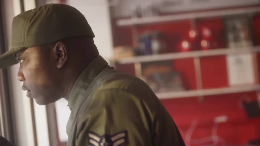 An airman puts his cap on and exits a shop