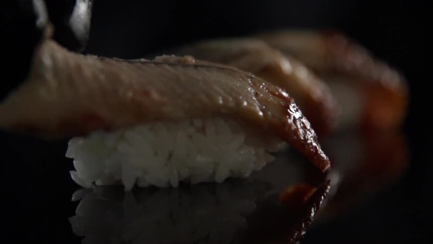 A slice of eel is placed on top of a ball of sushi rice