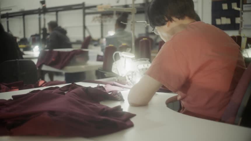 Several people in a room work at sewing machines