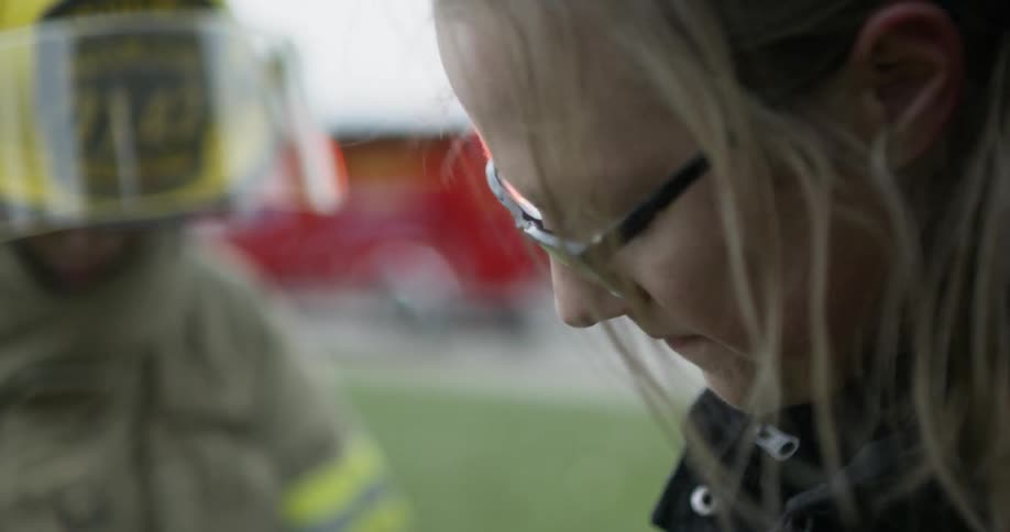 A paramedic cuts clothes from an injured firefighter