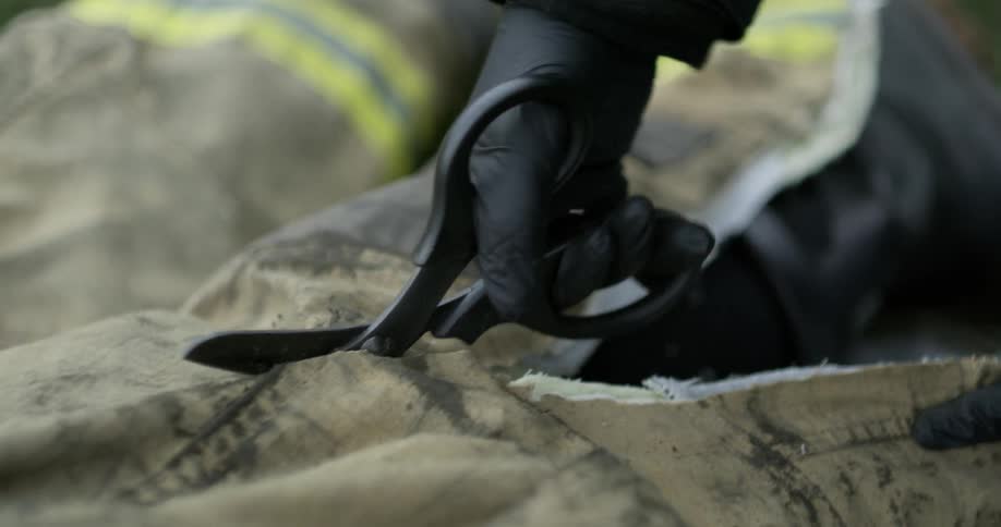 A firefighter's uniform is cut with scissors