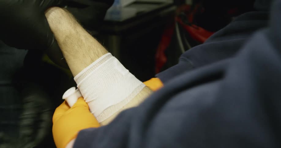 A man is having his arm wrapped by medics