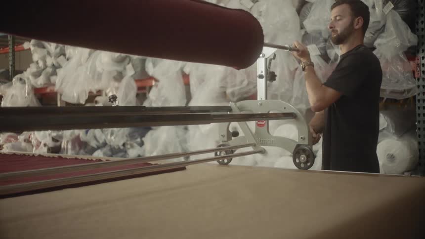 A man places a spool of fabric on a mechanism