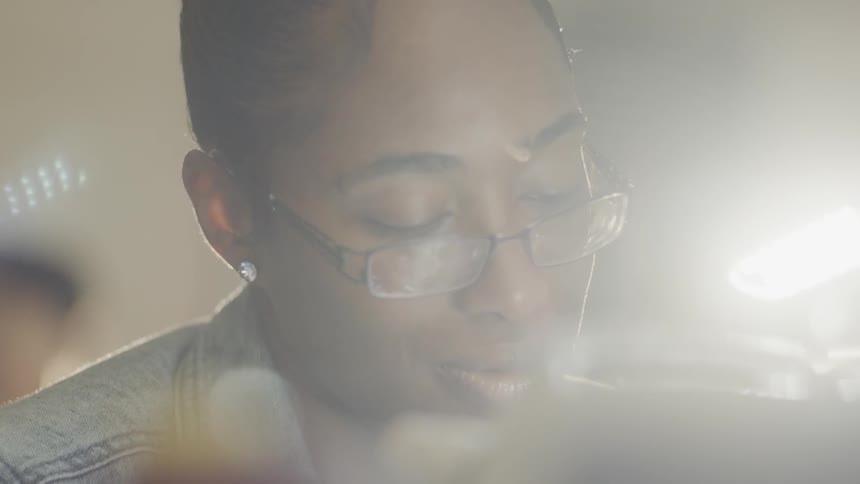 A woman wearing glasses looks down at what she is working on