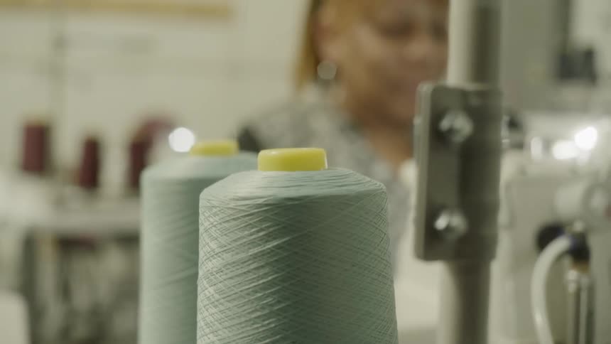 Thread from spools unwinds as people work on sewing machines
