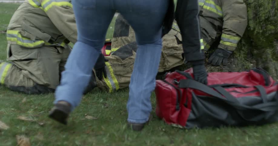An emt puts down a medical bag next to an injured firefighter