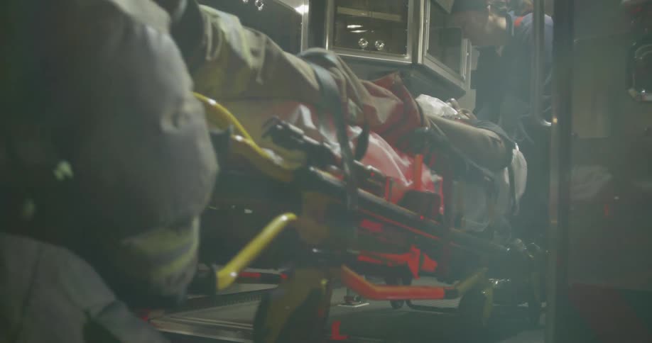 Paramedics load a stretcher into an ambulance