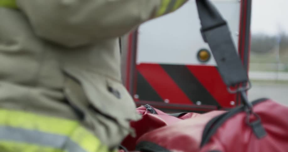 A firefighter carries a large red bag