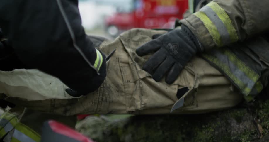 A paramedic cuts clothes from an injured firefighter