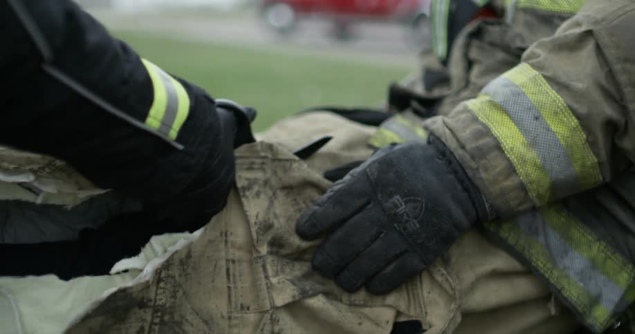 A paramedic cuts clothes from an injured firefighter