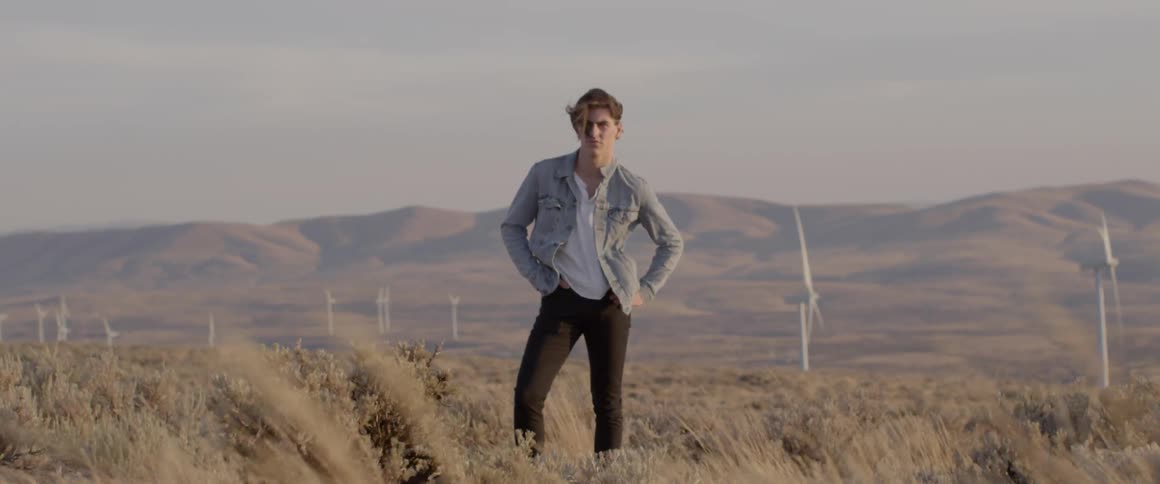 Man stands in a field near the turbines