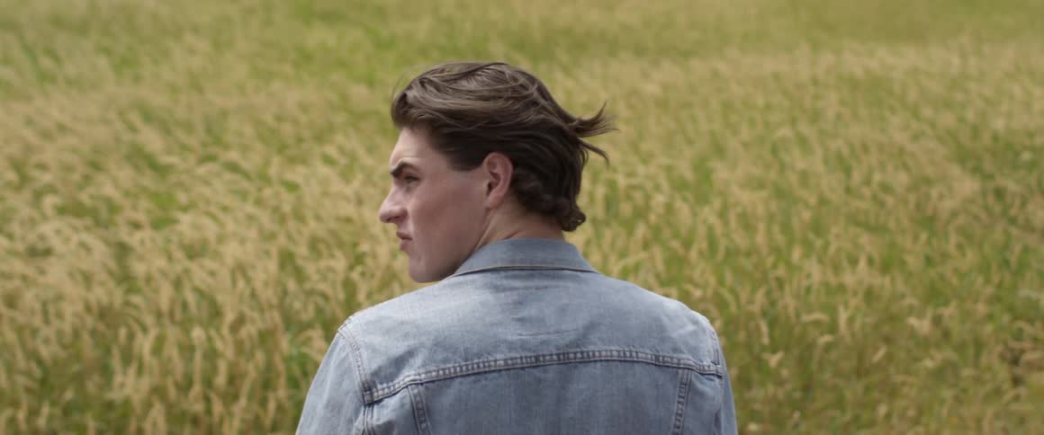 A man stands in a rural grassy field