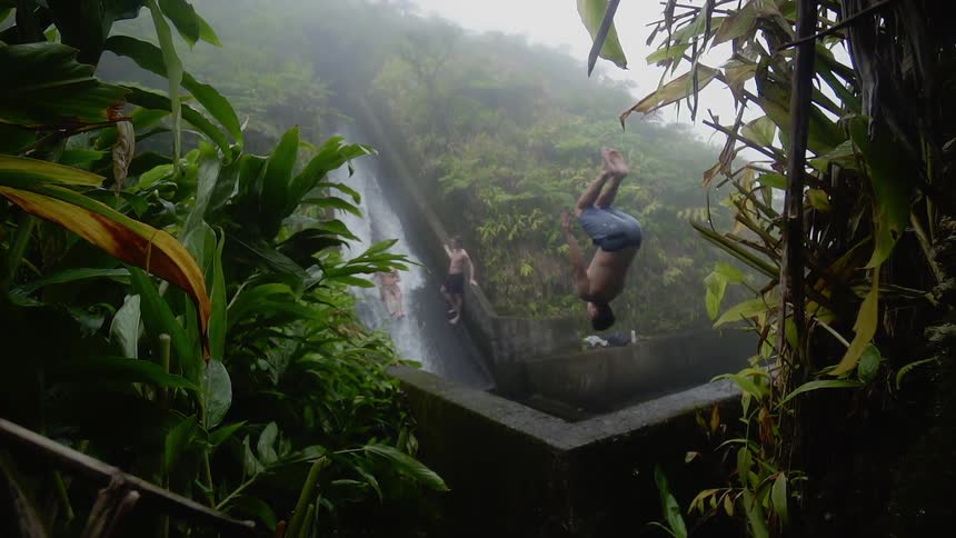 People jump into a waterfall spring
