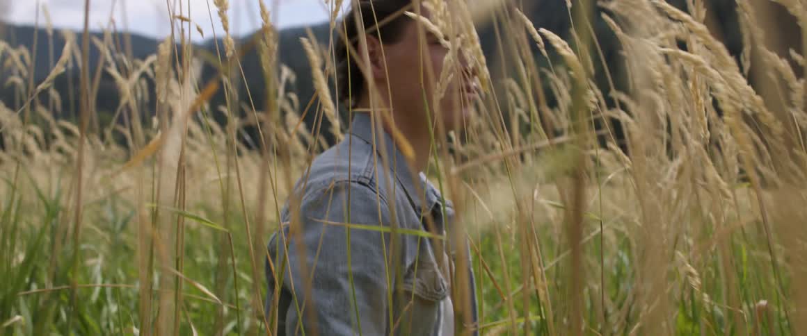 Man walks in nature among tall weeds