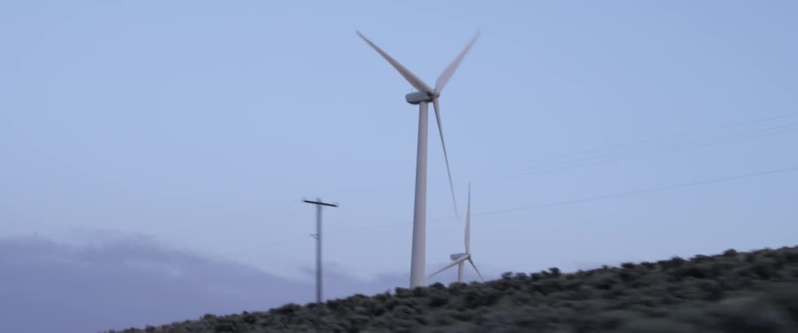 Wind turbines spin on a rural hill